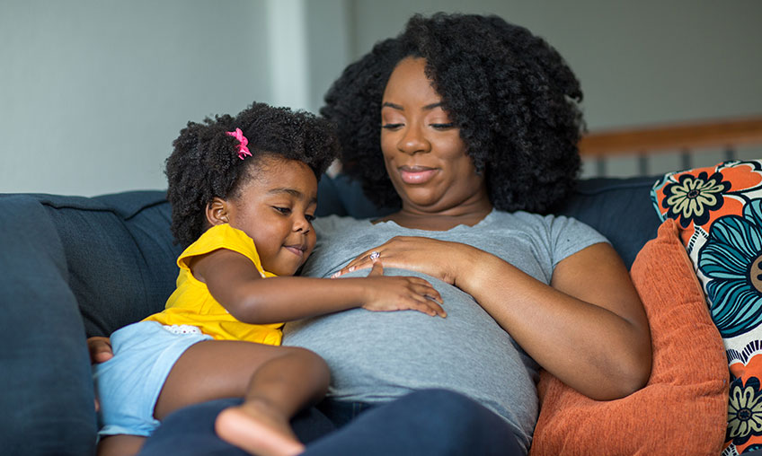 pregnant woman and daughter feeling belly