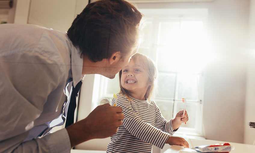 padre revisando los dientes de su hijo mientras se cepilla